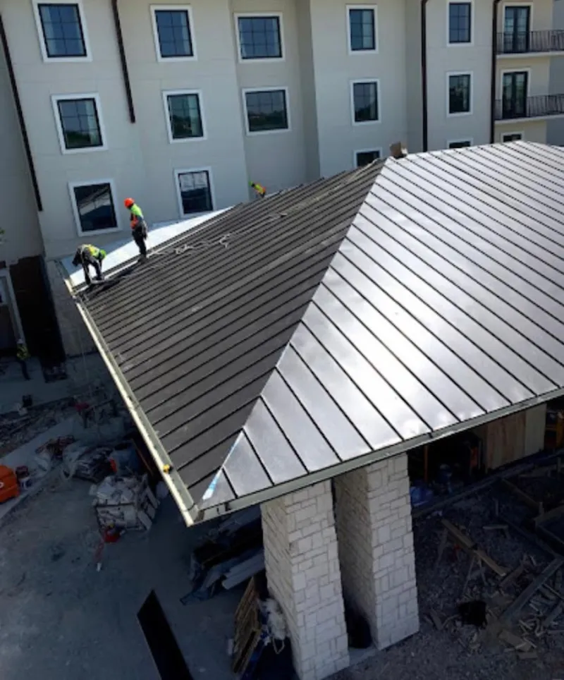 Crew installing standing seam metal roof panels on a commercial project in Old Fig Garden